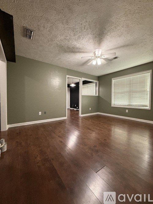 A room with a ceiling fan and wooden flooring.