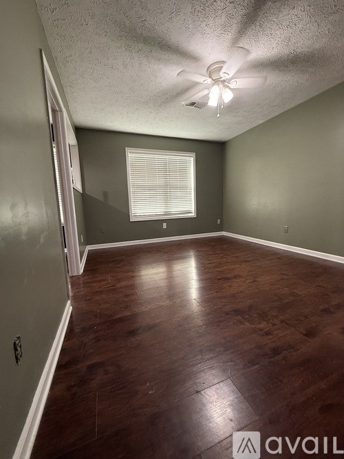 A room with a ceiling fan and wooden flooring.