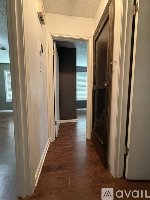 A hallway with a wooden door and a black chair.