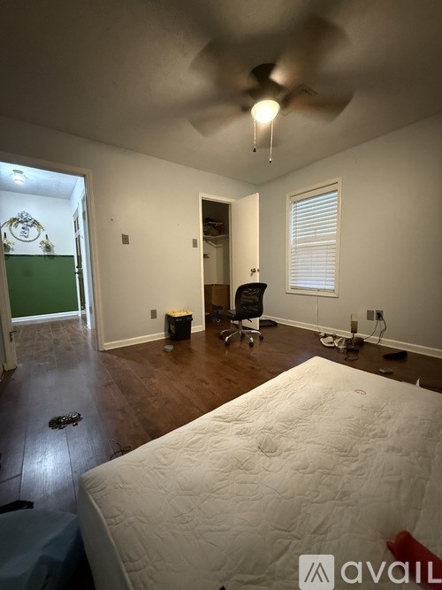 A bedroom with a bed, chair, and ceiling fan.
