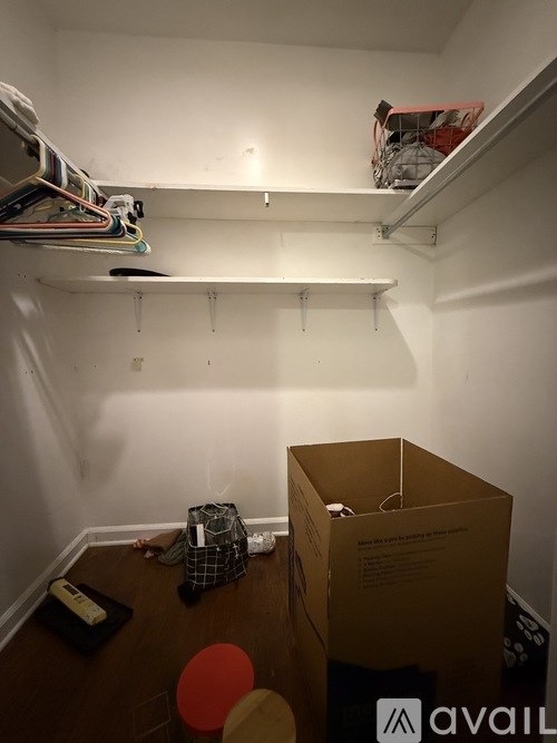 A room with a box on the floor and clothes hanging on the wall.