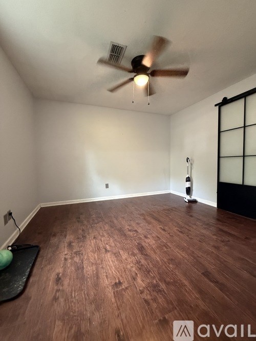 A room with a ceiling fan and wooden flooring.