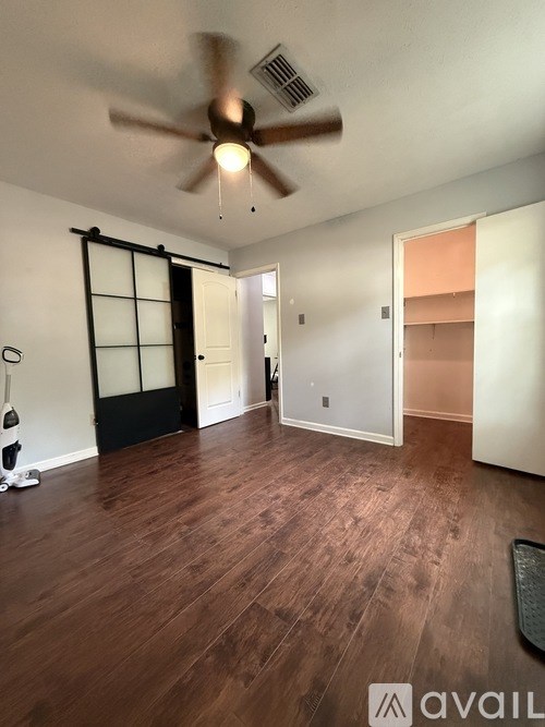 A room with a ceiling fan and wooden flooring.