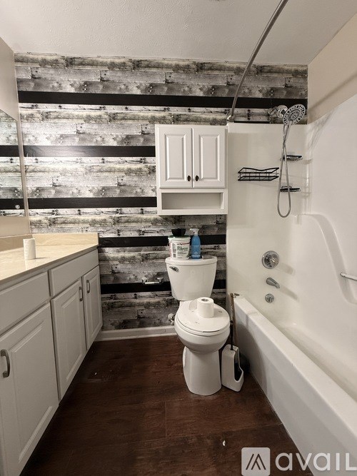 A white toilet sits in a bathroom with a wooden wall behind it.
