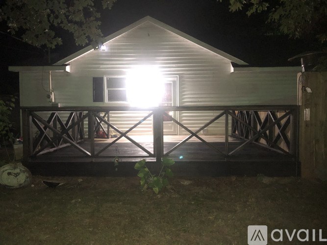 A house with a lit window and a porch at night.