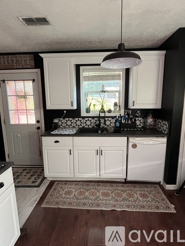 A kitchen with white cabinets and a rug on the floor.