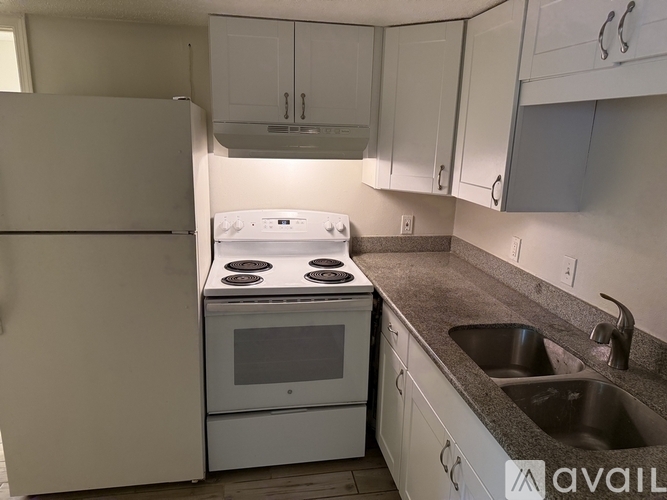 A white stove and refrigerator in a kitchen with white cabinets.