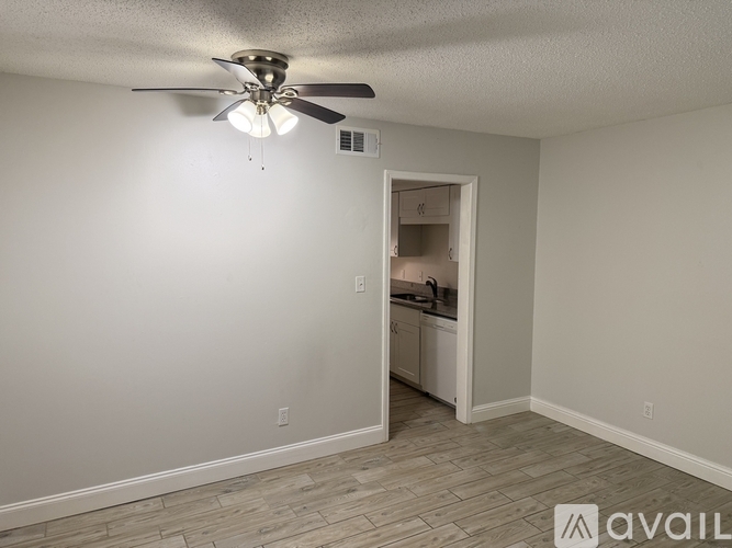 A room with a ceiling fan and a doorway leading to a kitchen.