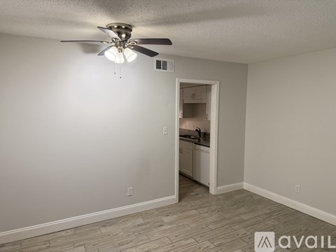 A room with a ceiling fan and a doorway leading to a kitchen.