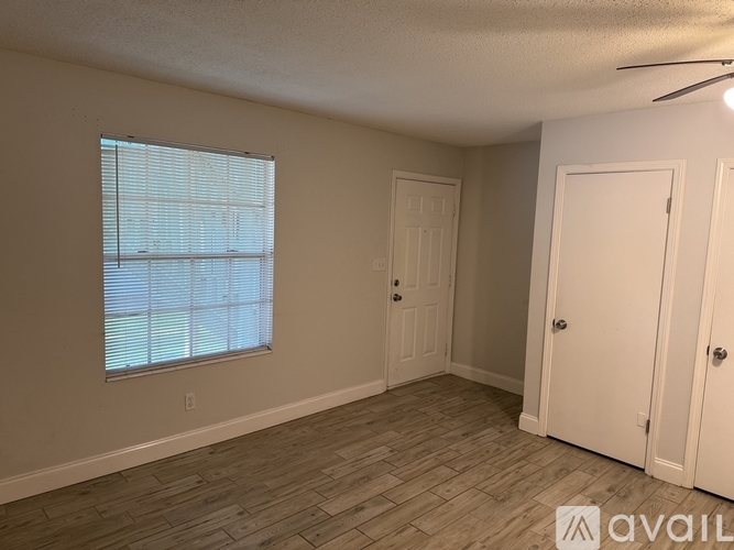 A room with a window, two doors, and a ceiling fan.