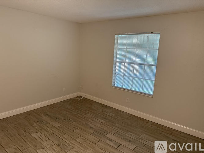 A room with a window and wooden flooring.