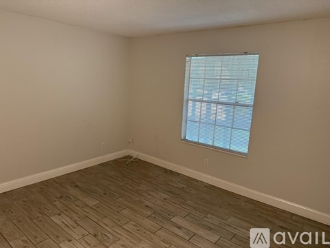A room with a window and wooden flooring.