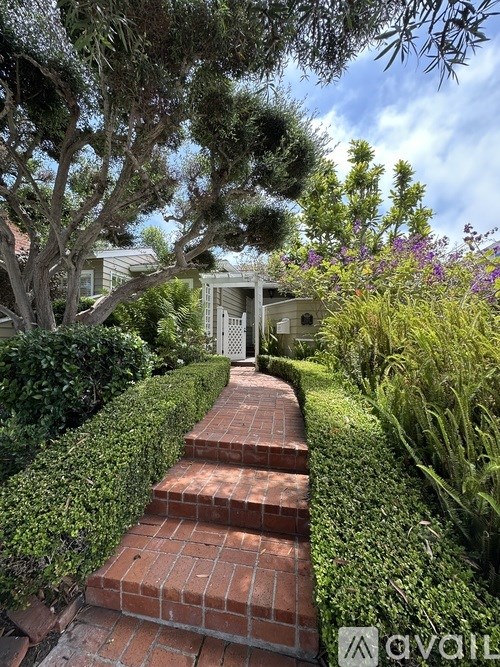 A pathway made of bricks leads to a white house.