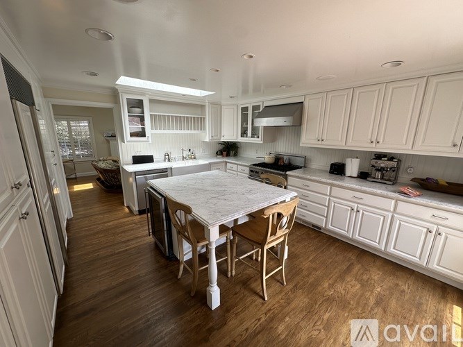 A kitchen with white cabinets and a wooden table.