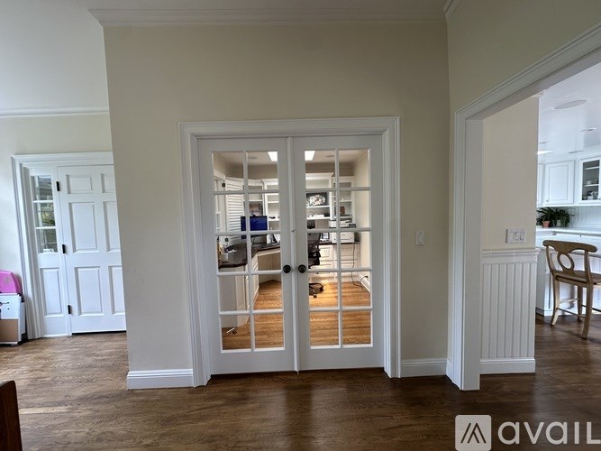 A white interior with a doorway leading to a kitchen.