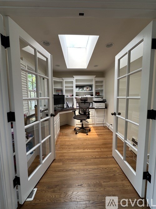 A home office with a skylight and a desk with a computer.