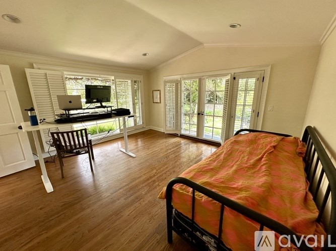 A bedroom with a bed, desk, and chair.