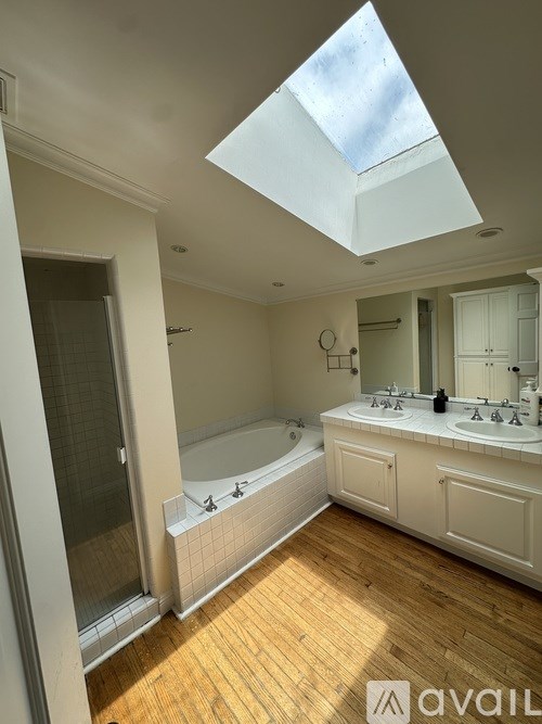 A bathroom with a skylight and wooden floors.