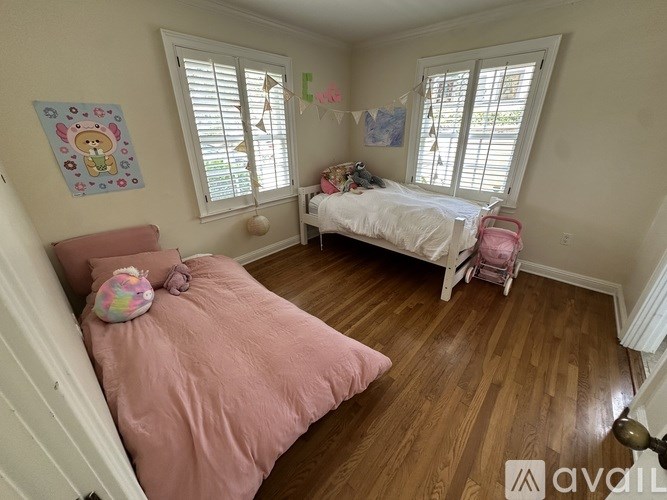 A bedroom with a pink bedspread and a white bed.