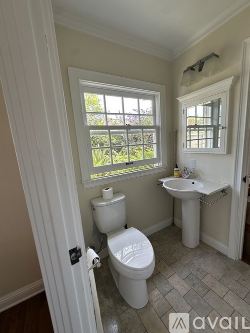 A bathroom with a toilet, sink, and window.