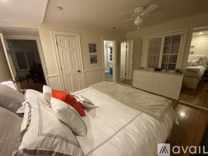 A bedroom with a bed, pillows, and a ceiling fan.