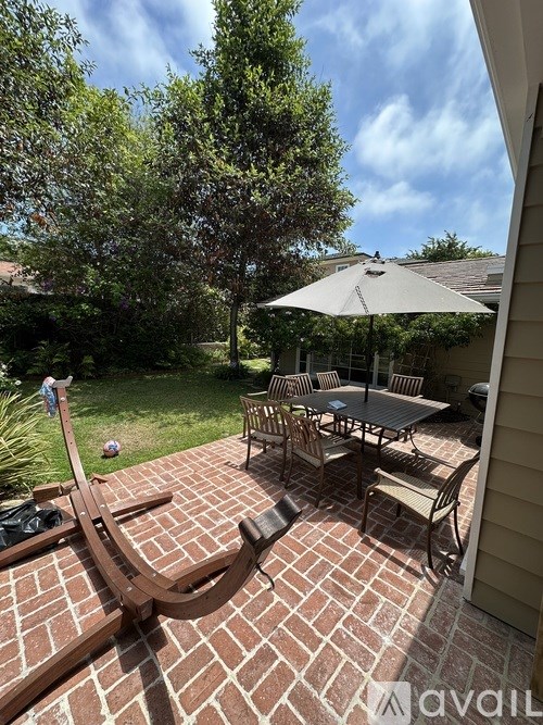 A patio with a table and chairs and an umbrella.