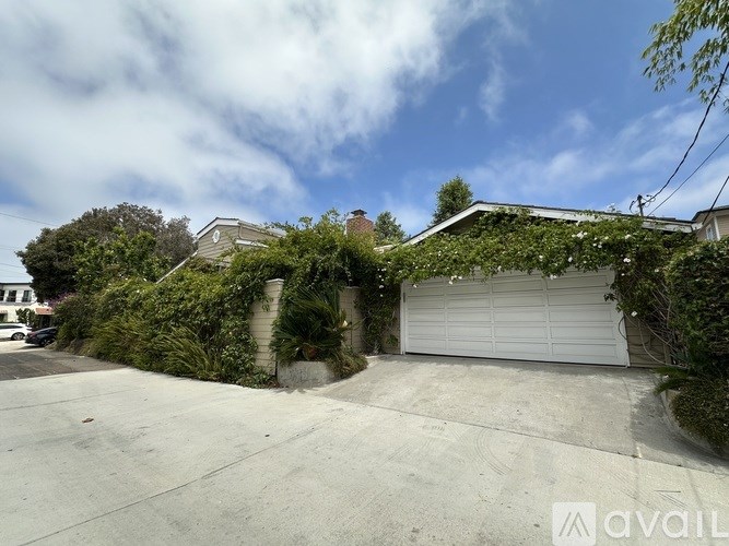 A house with a garage covered in greenery.
