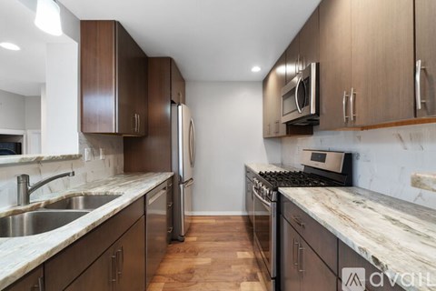 A kitchen with dark wood cabinets and marble countertops.