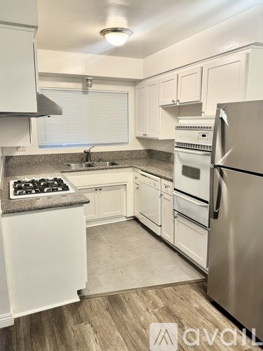 A kitchen with white cabinets and a stainless steel refrigerator.