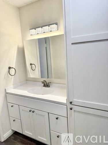 A white bathroom vanity with a sink and mirror.
