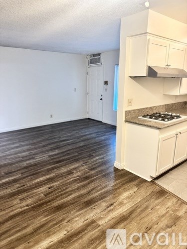 A kitchen with white cabinets and a wooden floor.