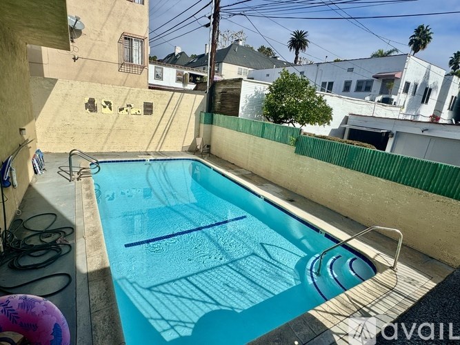 A small residential pool with a ladder and a fence.