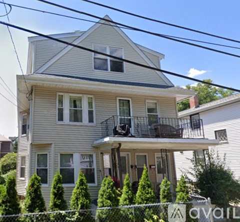A house with a grey siding and a balcony with a black railing.