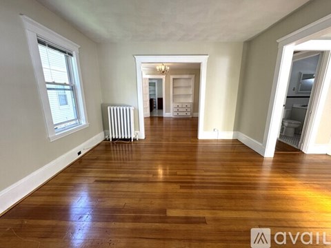 A spacious room with wooden floors and a white radiator.