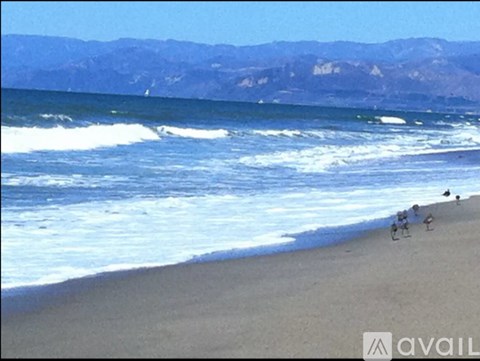A beach scene with people on the sand and waves crashing in.