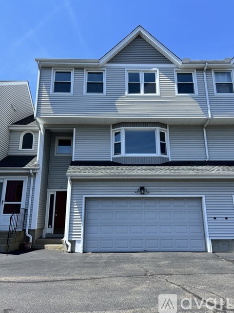 A two-story house with a garage door and a window on each floor.