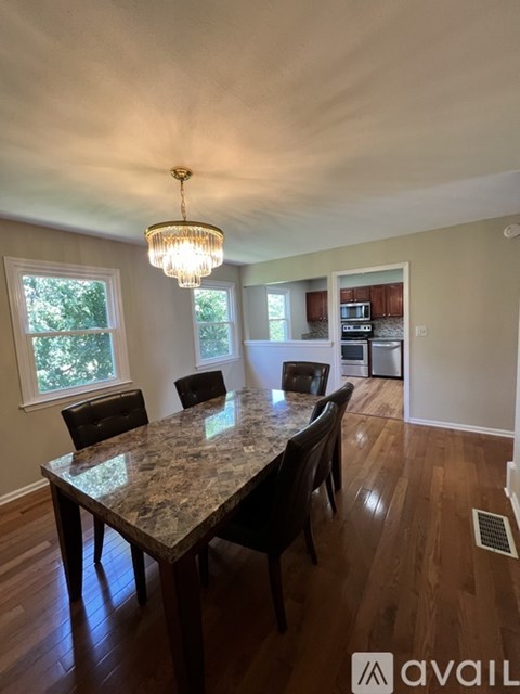 A kitchen with a granite countertop and a dining table with chairs.