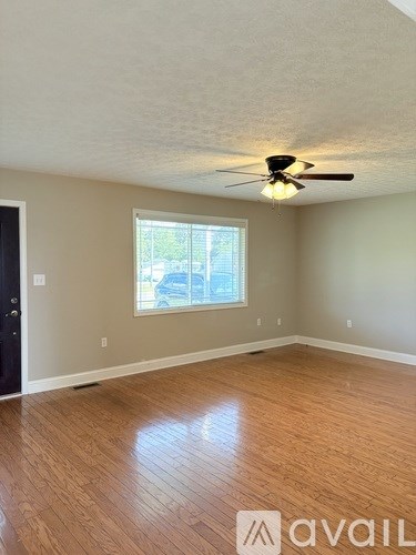 A room with a ceiling fan and wooden flooring.