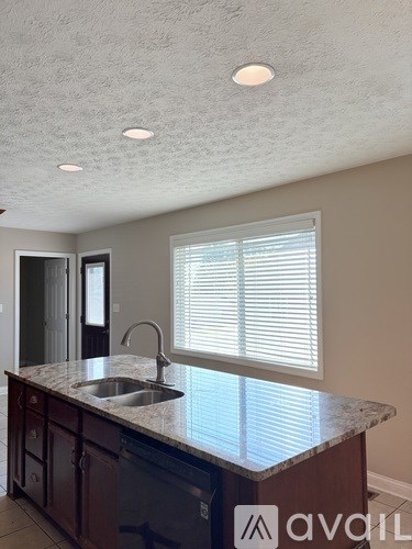A kitchen with a sink and a window with blinds.