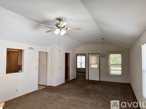 A spacious room with a ceiling fan and carpeted floor.