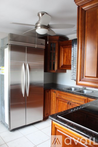 A kitchen with a stainless steel refrigerator and wooden cabinets.