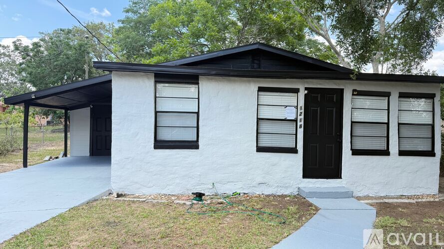 A white house with a black door and windows is for sale.