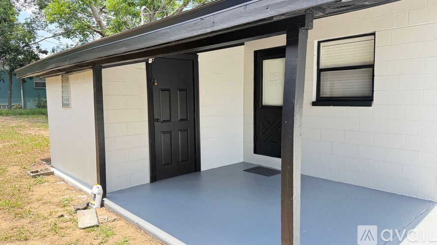 A small white house with a black door and a black awning.