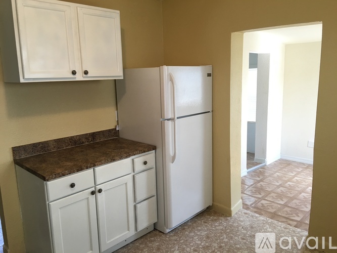 A kitchen with a white refrigerator and cabinets.