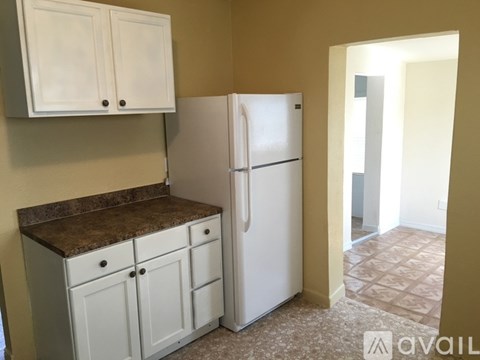 A kitchen with a white refrigerator and cabinets.