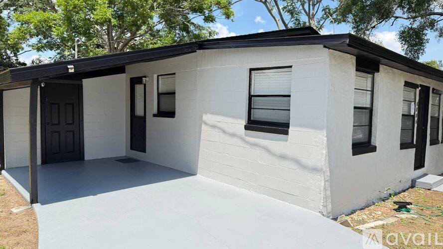 A white house with a black door and windows is available for purchase.