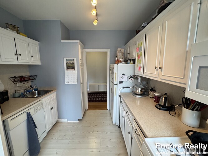 A kitchen with white cabinets and a white refrigerator.