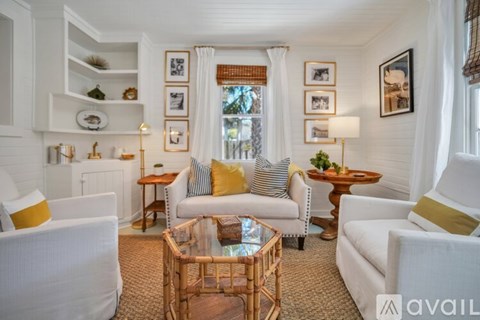 A living room with white furniture and a glass coffee table.