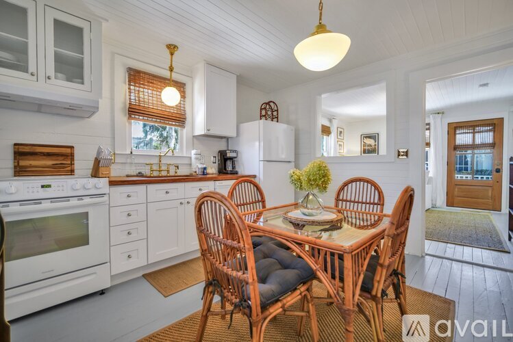 A kitchen with a table and chairs in the foreground and a doorway leading to another room in the background.