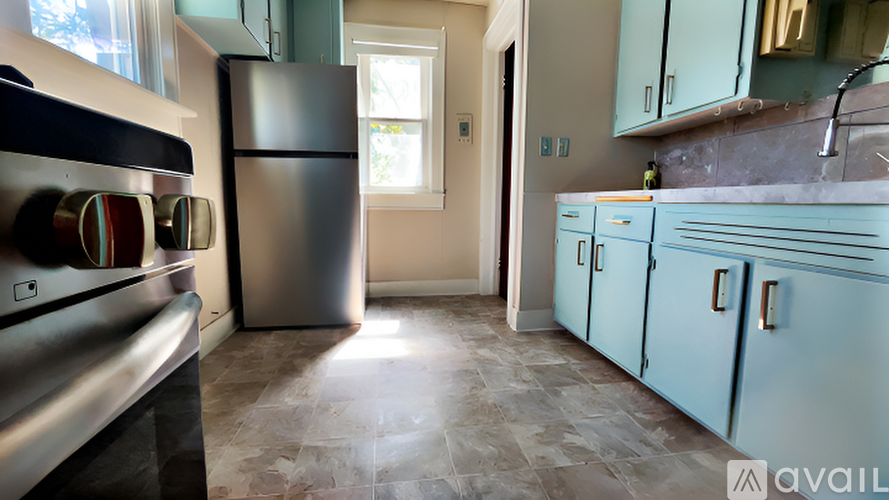 A kitchen with blue cabinets and a stone backsplash.